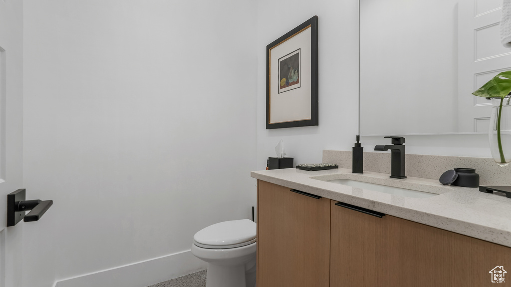 Bathroom with vanity, toilet, and baseboards