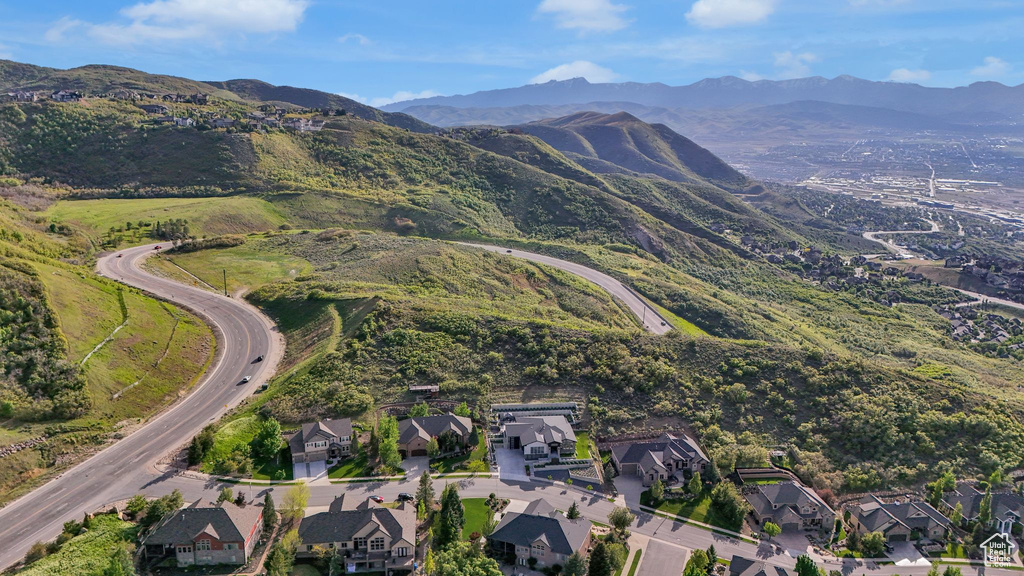 Aerial view of property and surrounding area featuring nearby suburban area and a mountain backdrop