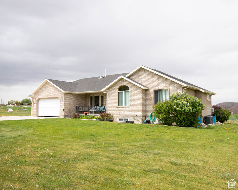 Single story home with brick siding, an attached garage, a front yard, and concrete driveway