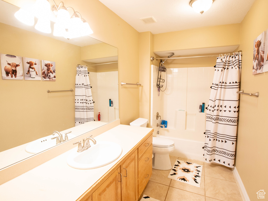 Full bathroom with tile patterned floors, toilet, vanity, and shower / bath combo with shower curtain