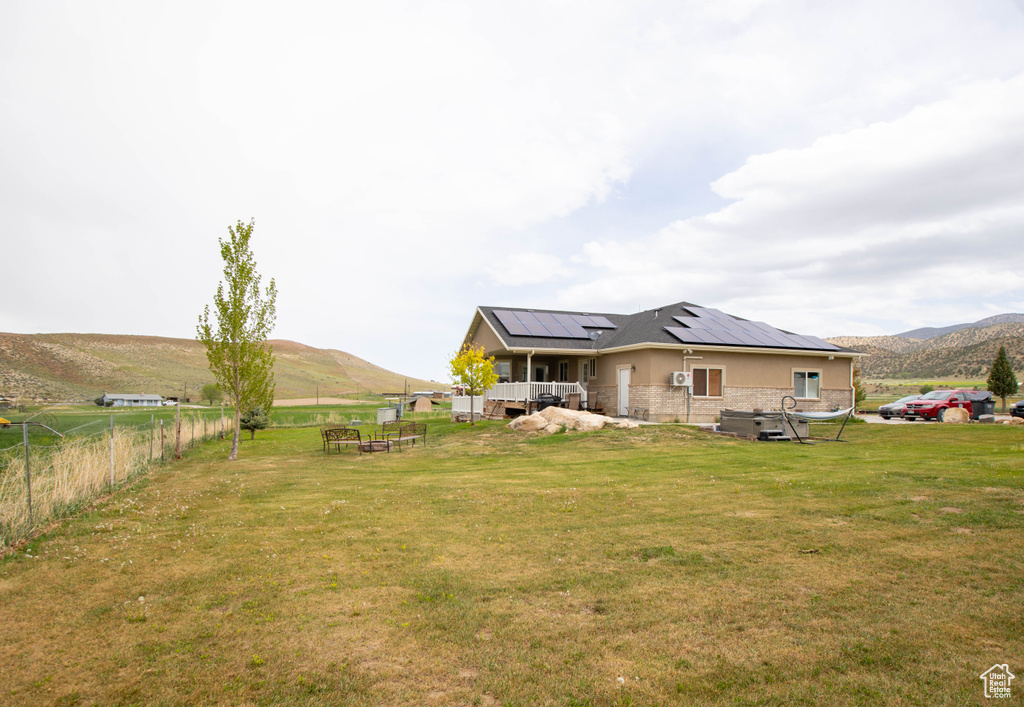 Back of house with roof mounted solar panels, a mountain view, and a view of rural / pastoral area
