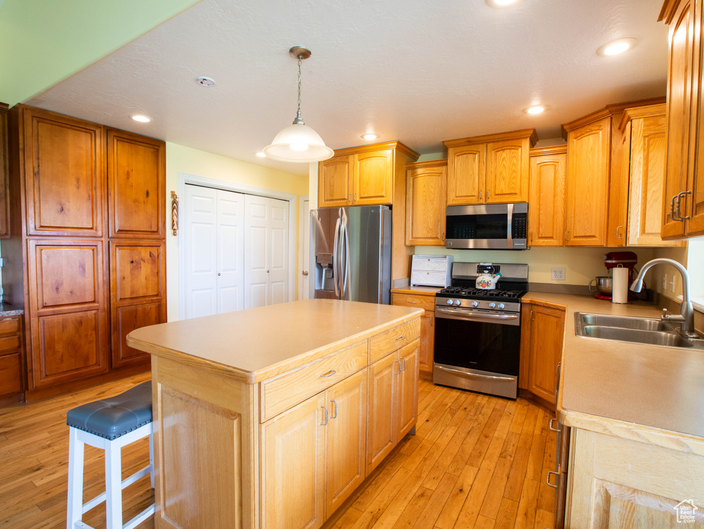 Kitchen featuring appliances with stainless steel finishes, a sink, light wood-style flooring, light countertops, and recessed lighting