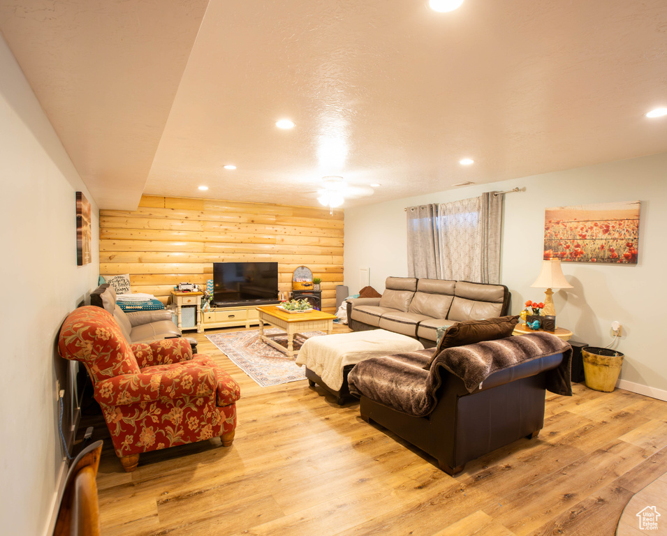 Living area with light wood-type flooring, log walls, recessed lighting, and baseboards