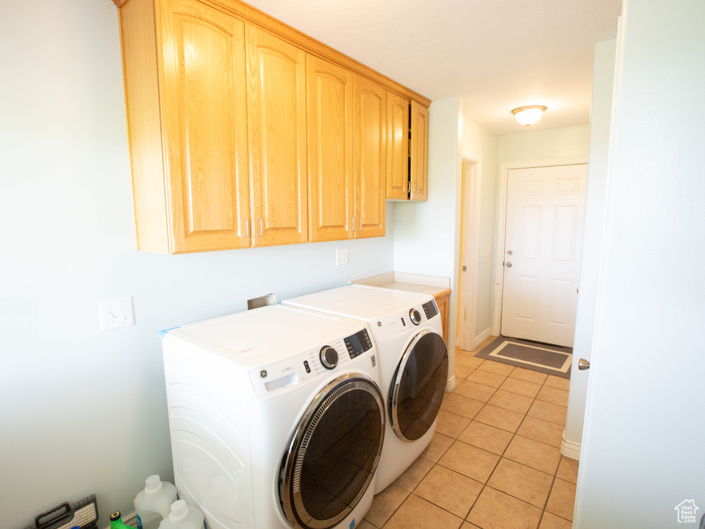 Laundry room featuring cabinet space, washing machine and dryer, light tile patterned floors, and baseboards