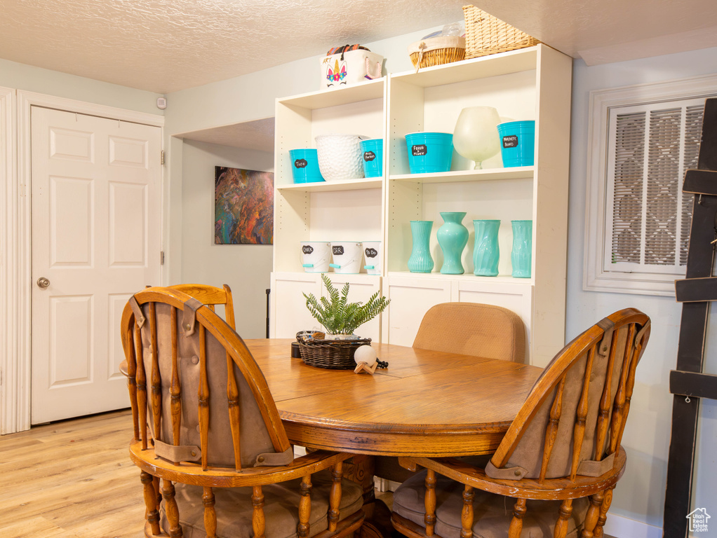 Dining room featuring light wood-style floors and a textured ceiling