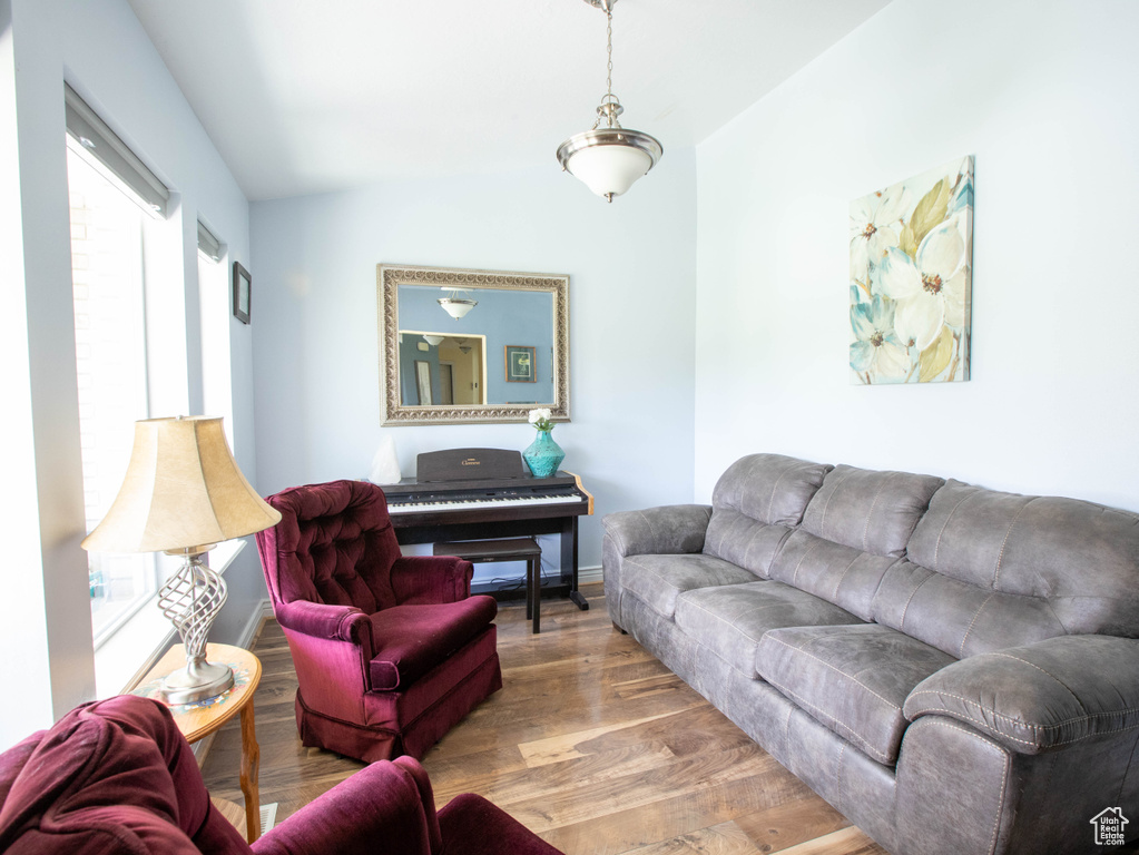 Living room featuring wood finished floors, lofted ceiling, and baseboards