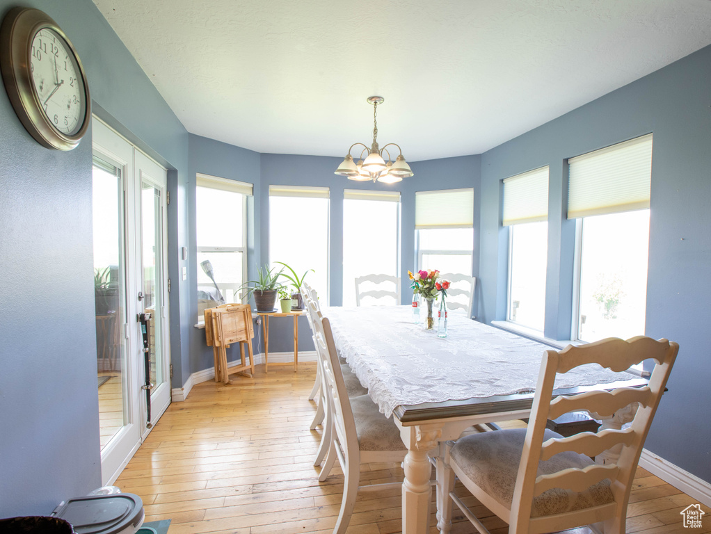 Dining space featuring light wood-style floors, a chandelier, and baseboards