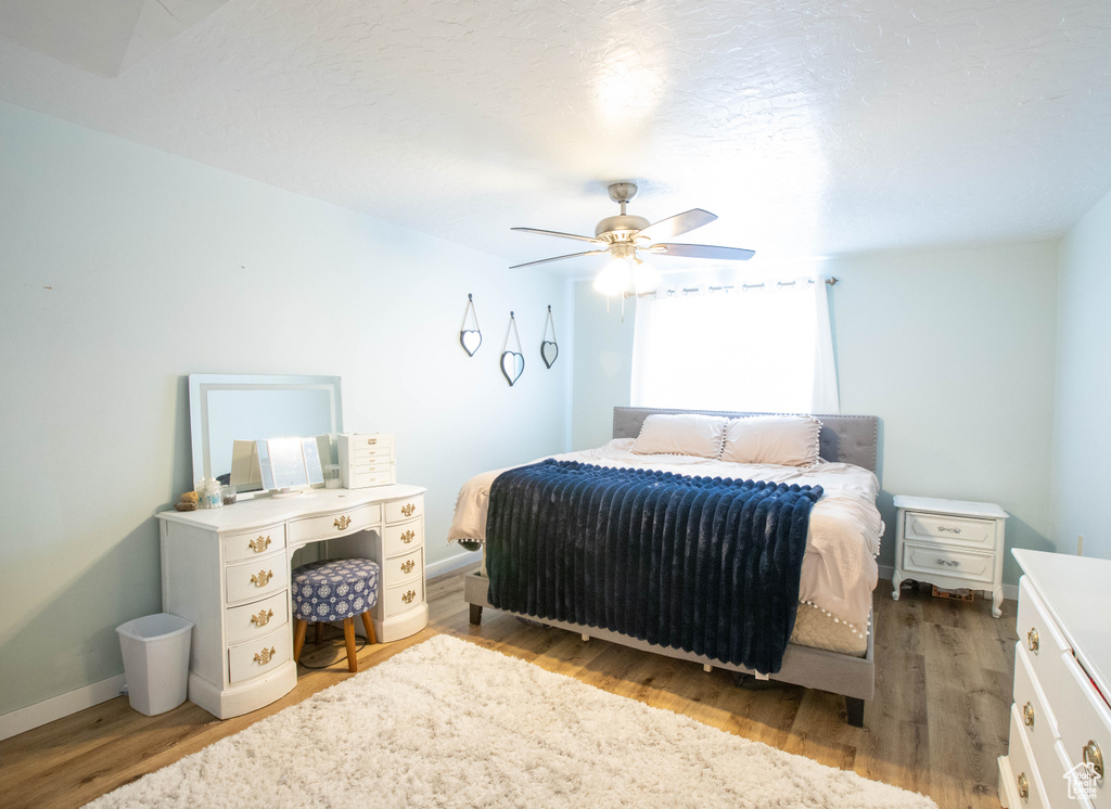 Bedroom featuring wood finished floors, baseboards, and a ceiling fan