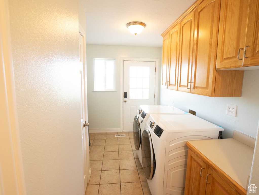 Clothes washing area featuring cabinet space, separate washer and dryer, baseboards, and light tile patterned floors