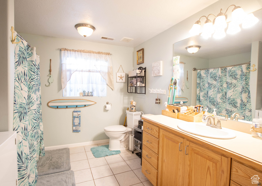 Full bathroom with toilet, vanity, and tile patterned floors