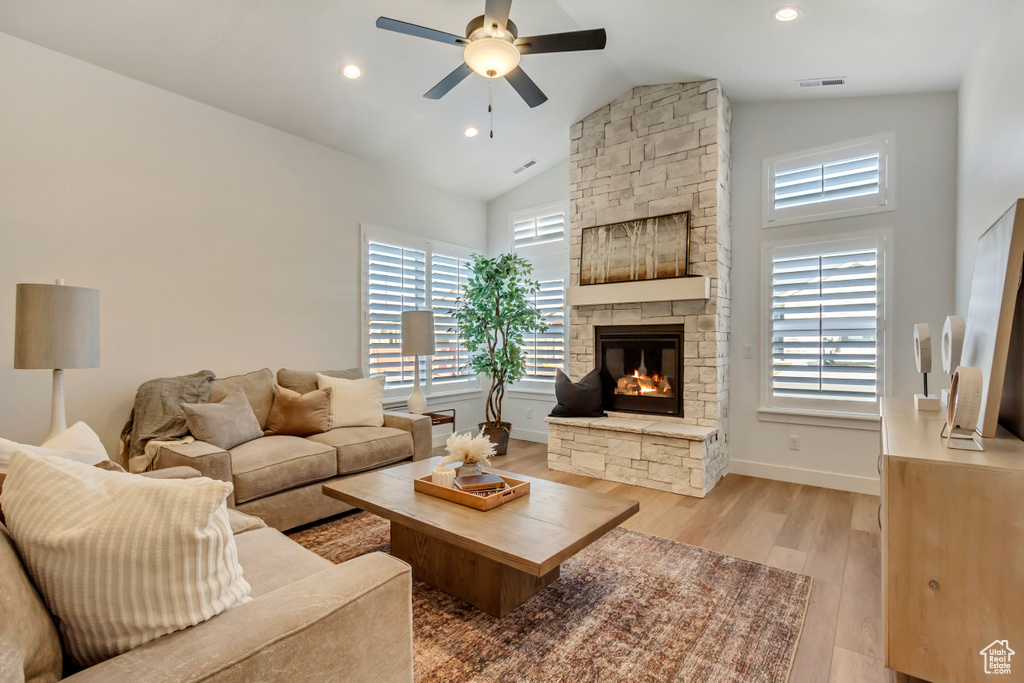 Living area with ceiling fan, a fireplace, light wood-style flooring, high vaulted ceiling, and recessed lighting