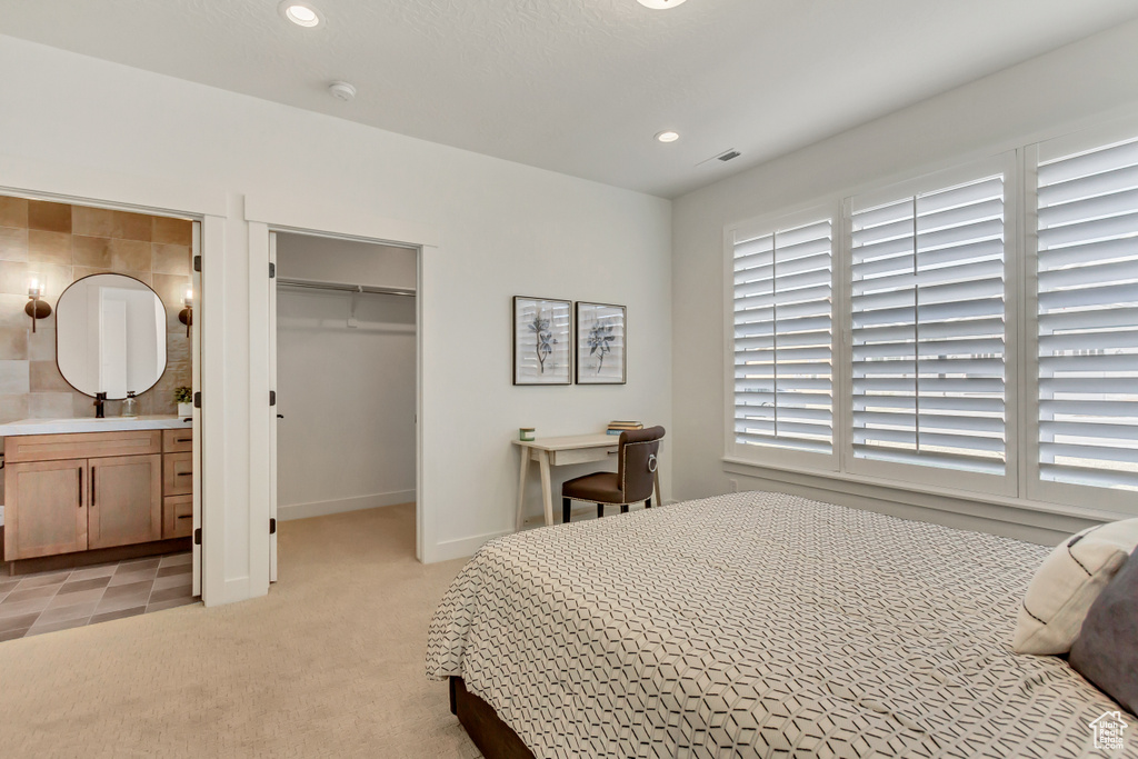 Bedroom with a spacious closet, recessed lighting, a closet, ensuite bathroom, and light carpet