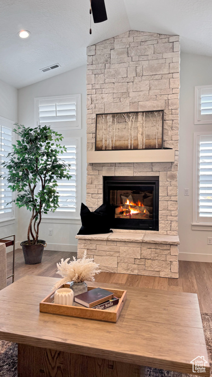 Living room with lofted ceiling, a ceiling fan, wood finished floors, a fireplace, and baseboards