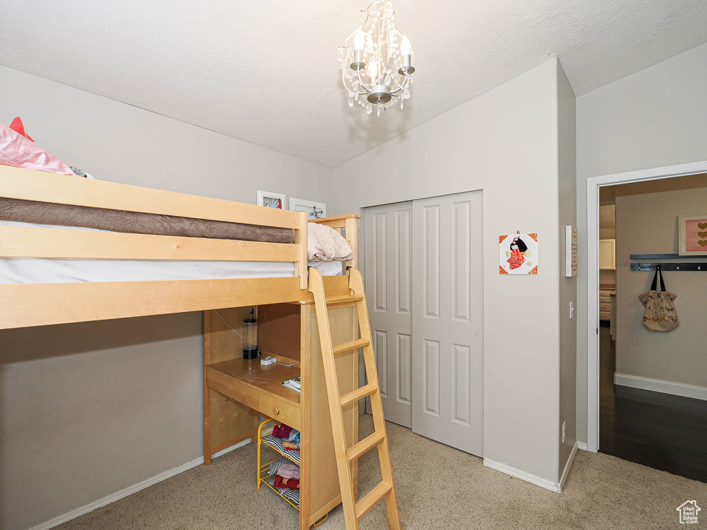 Carpeted bedroom with baseboards, a chandelier, and lofted ceiling