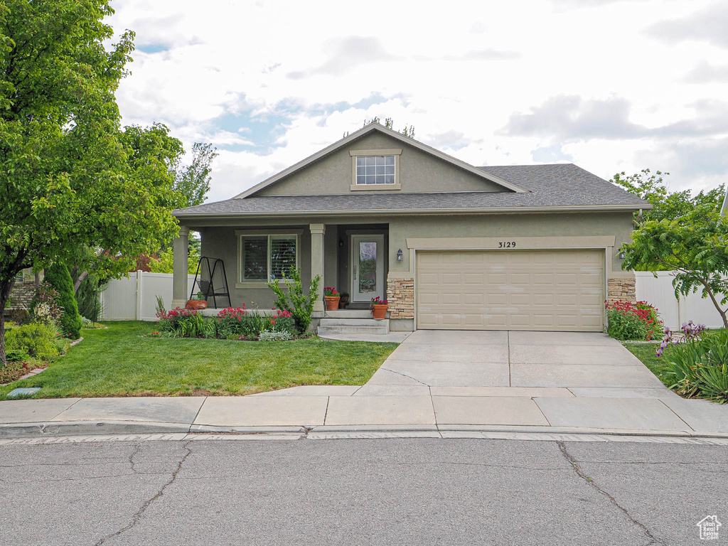 View of front facade featuring stucco siding, driveway, a garage, and stone siding