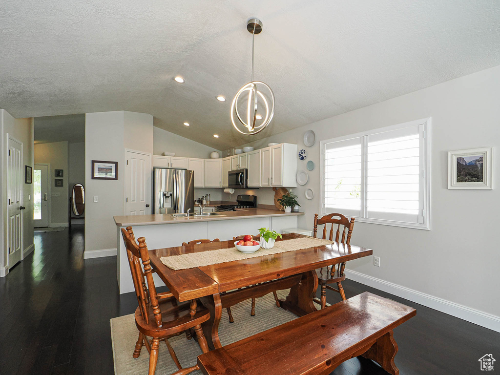 Dining space featuring lofted ceiling, dark wood-style floors, baseboards, recessed lighting, and a chandelier