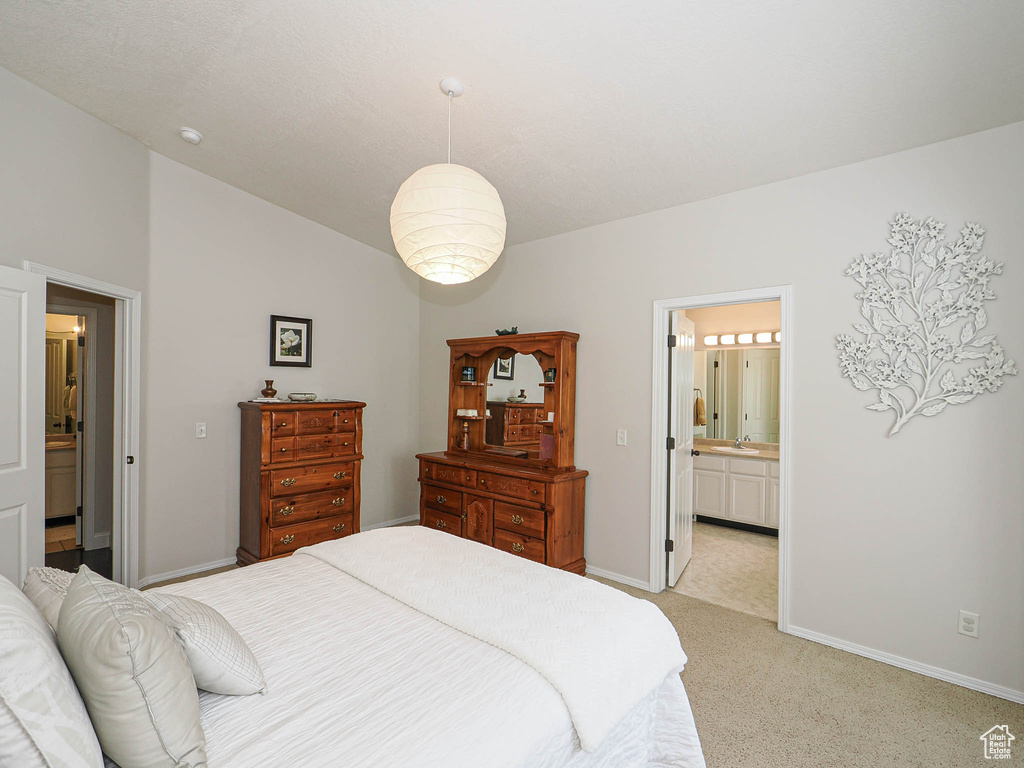 Bedroom with baseboards, light carpet, ensuite bath, and lofted ceiling