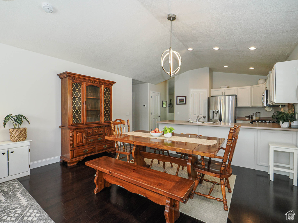 Dining room with vaulted ceiling, recessed lighting, dark wood finished floors, a chandelier, and baseboards