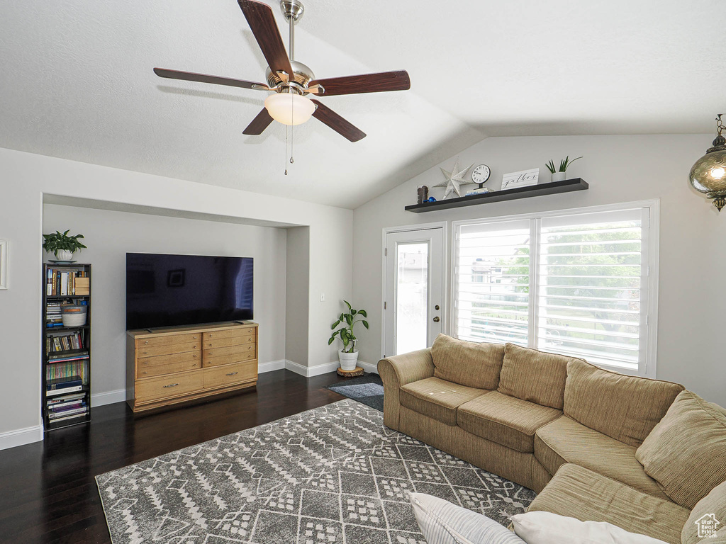 Living room featuring lofted ceiling, ceiling fan, wood finished floors, healthy amount of natural light, and baseboards