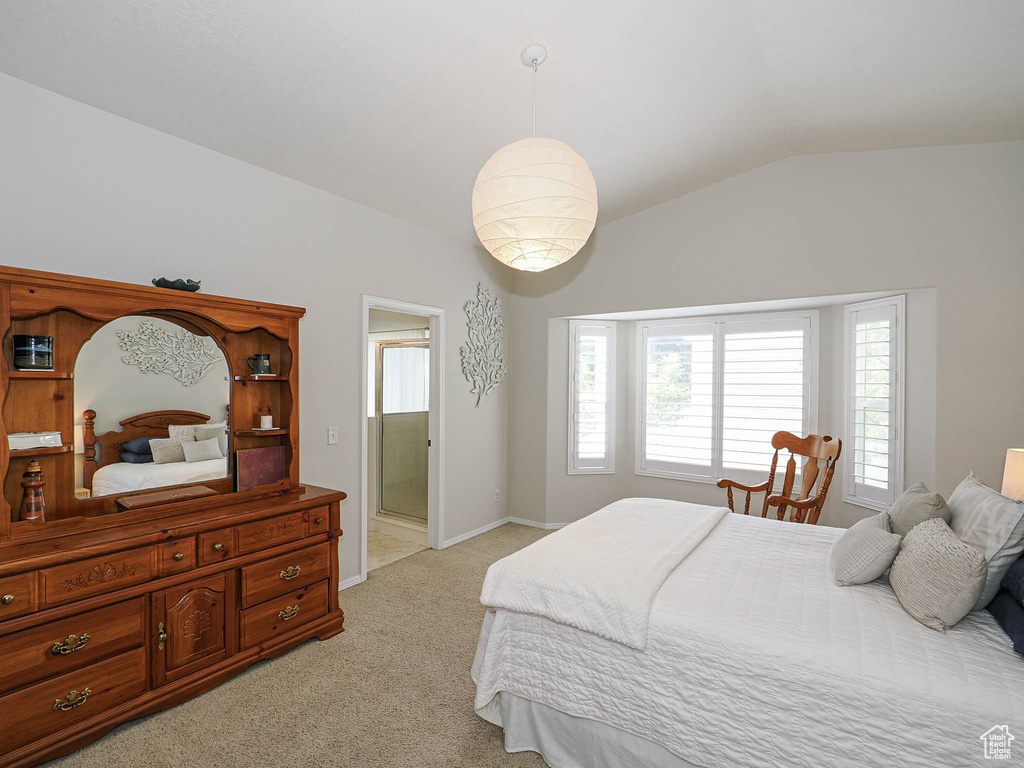 Bedroom featuring light colored carpet, lofted ceiling, baseboards, and ensuite bath