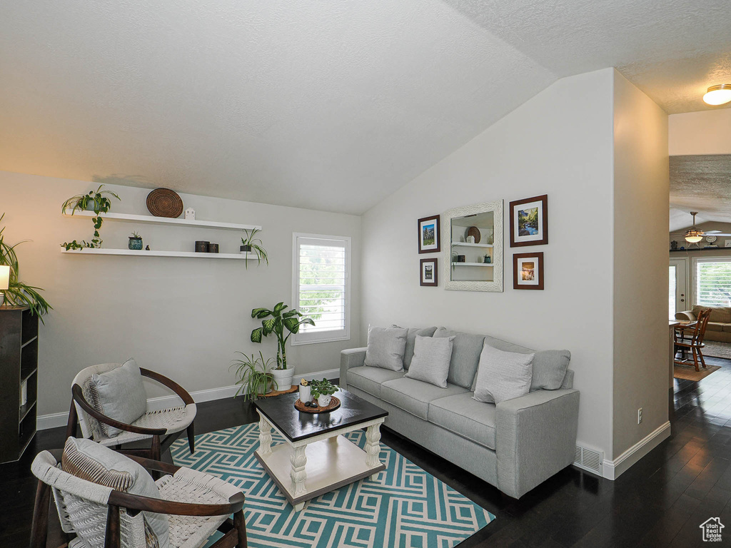 Living area with hardwood / wood-style flooring, lofted ceiling, baseboards, and a textured ceiling