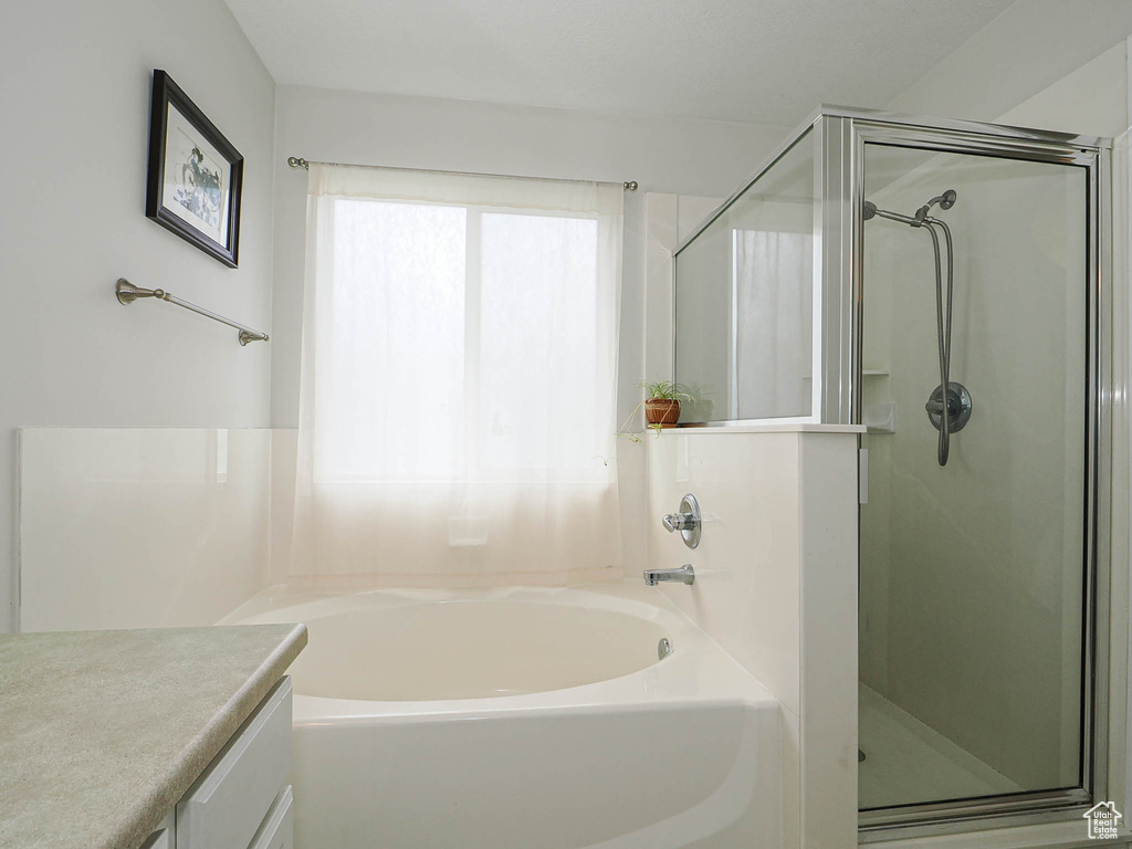Bathroom with a stall shower, a bath, and vanity