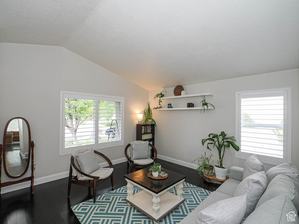 Living area with lofted ceiling, wood finished floors, a textured ceiling, and baseboards
