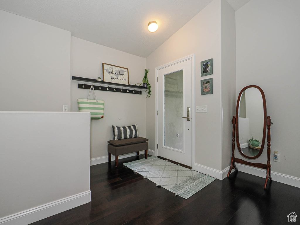 Foyer entrance with wood finished floors, baseboards, and vaulted ceiling