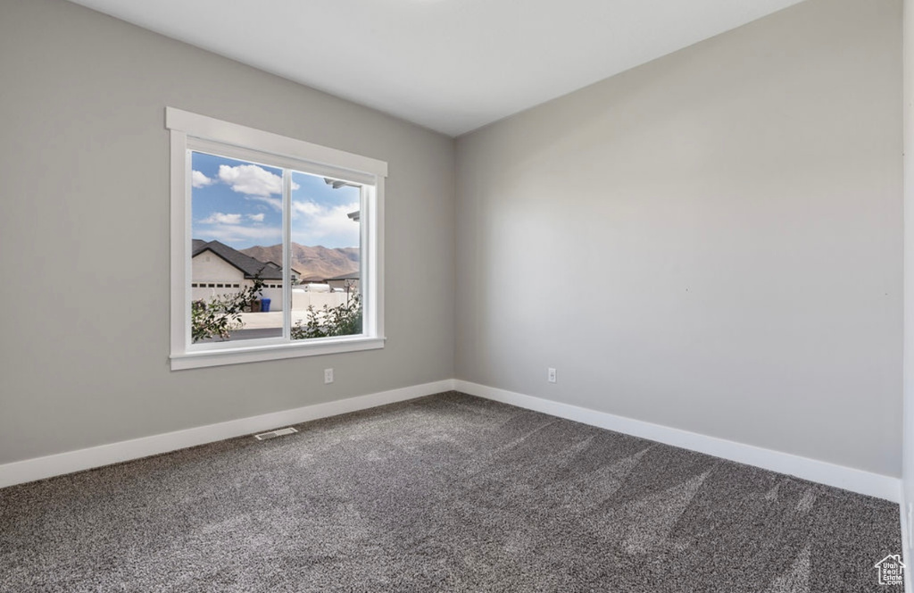Spare room featuring dark carpet and baseboards
