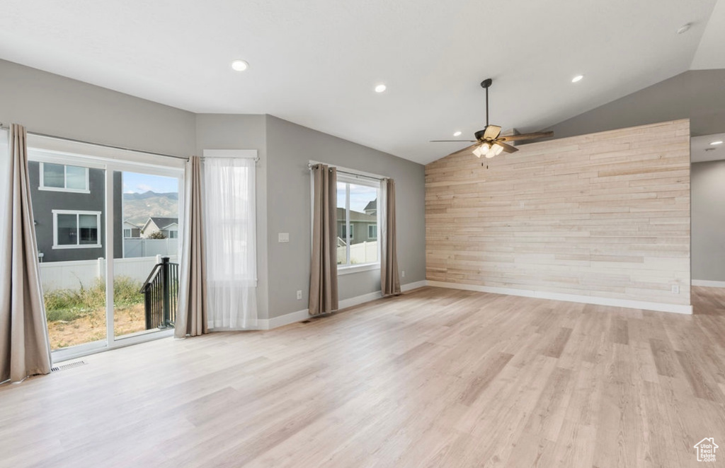 Unfurnished living room with lofted ceiling, ceiling fan, healthy amount of natural light, light wood finished floors, and recessed lighting