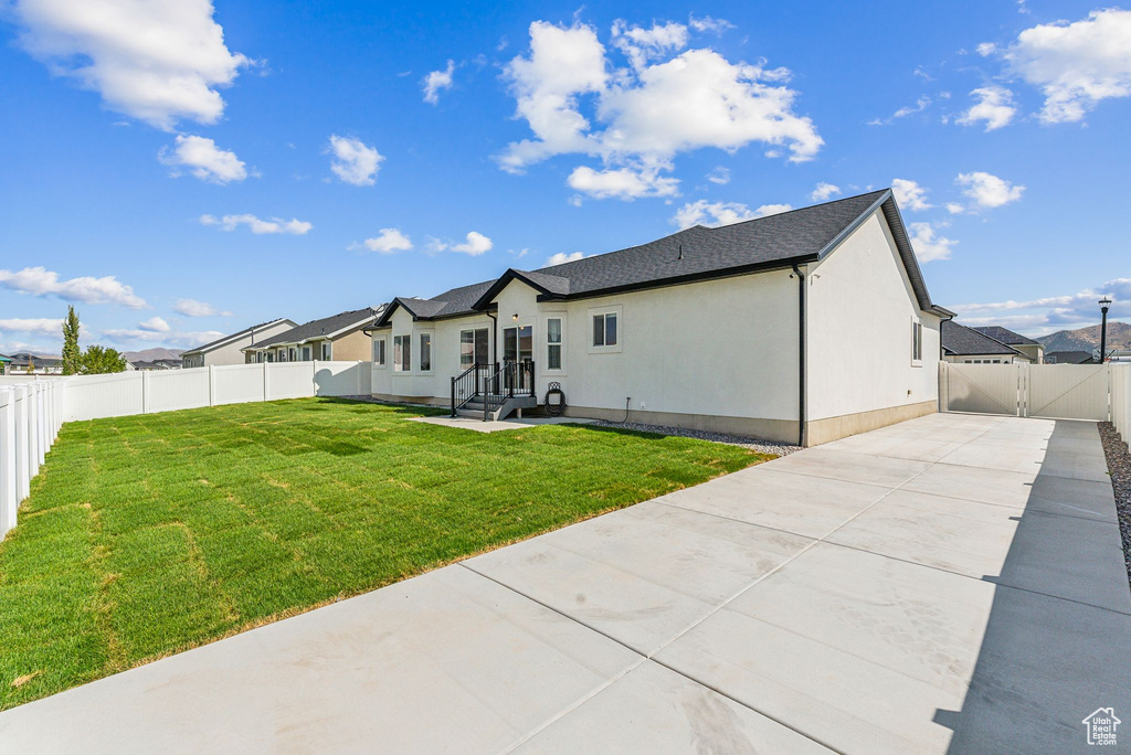 Rear view of property with a patio area, a gate, concrete driveway, and stucco siding