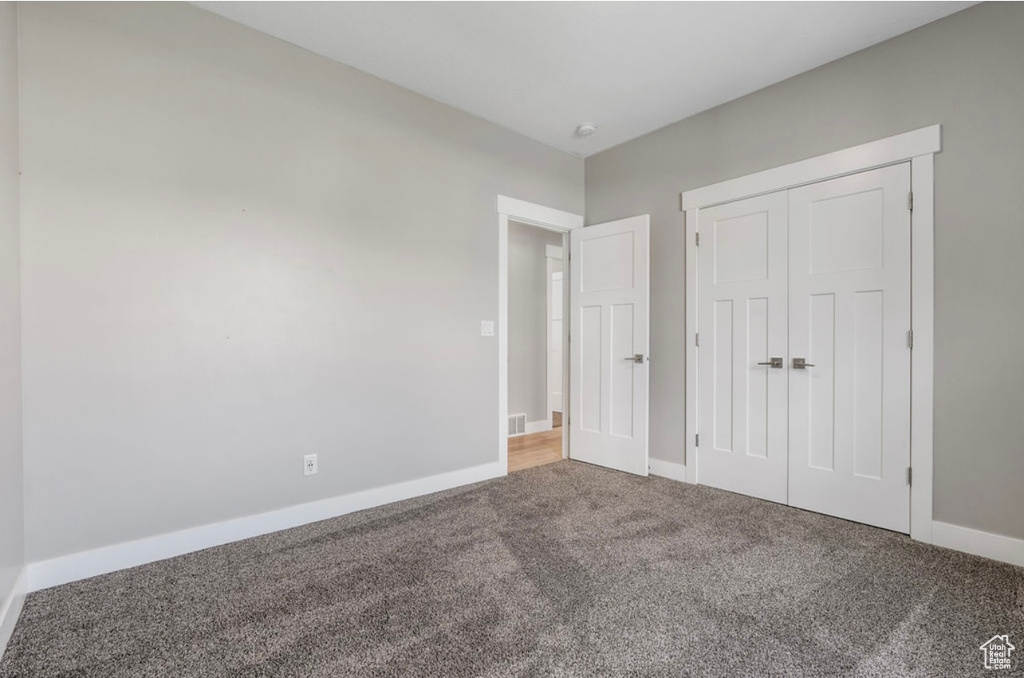Unfurnished bedroom with carpet flooring, baseboards, and a closet