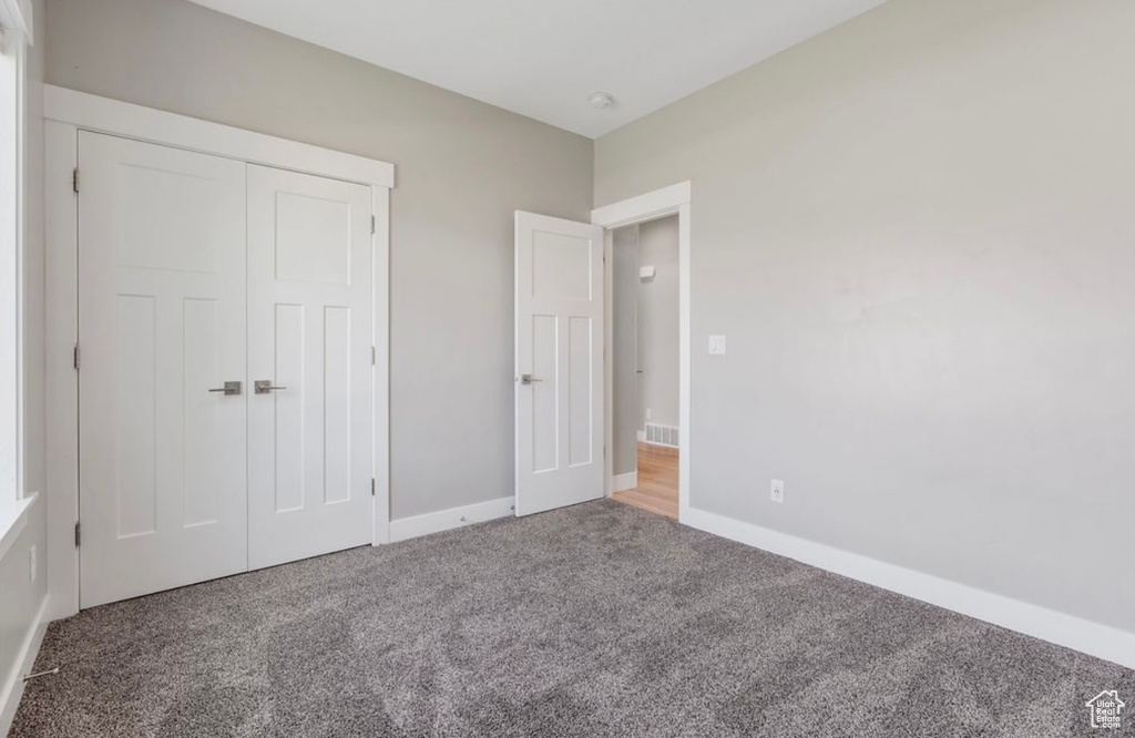 Unfurnished bedroom with carpet floors, a closet, and baseboards