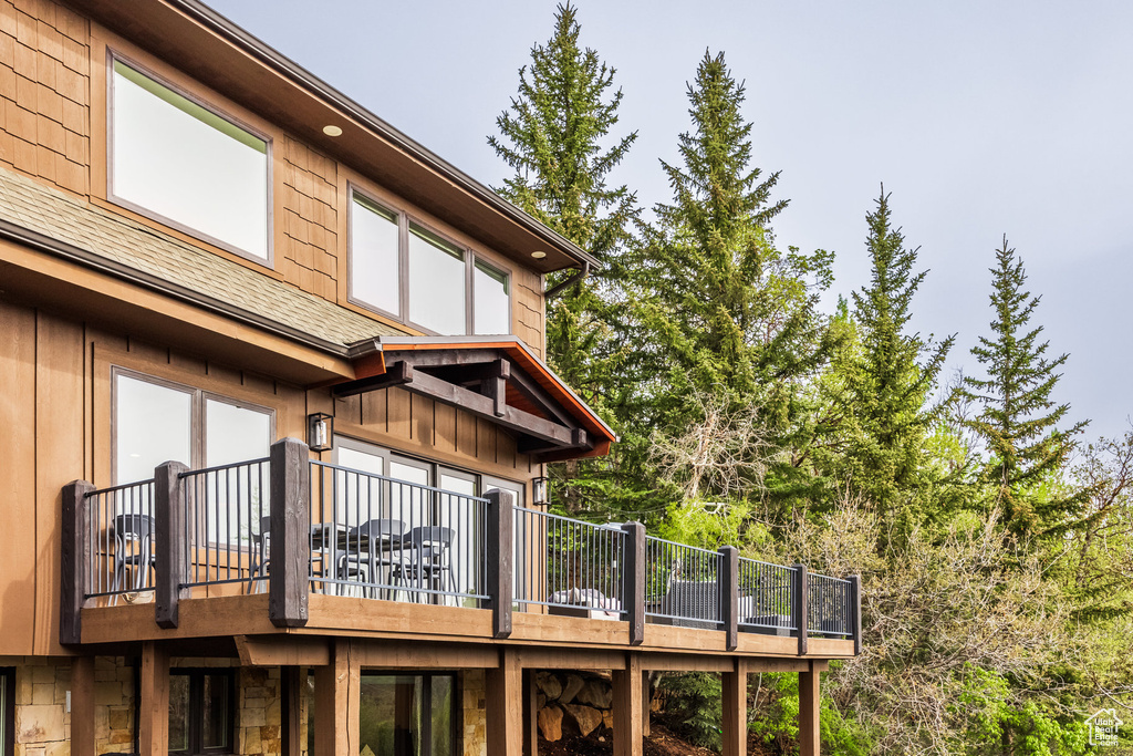 Back of house featuring stone siding and a shingled roof