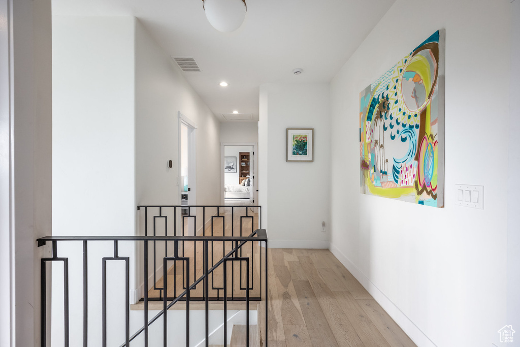 Corridor with an upstairs landing, wood finished floors, recessed lighting, and baseboards