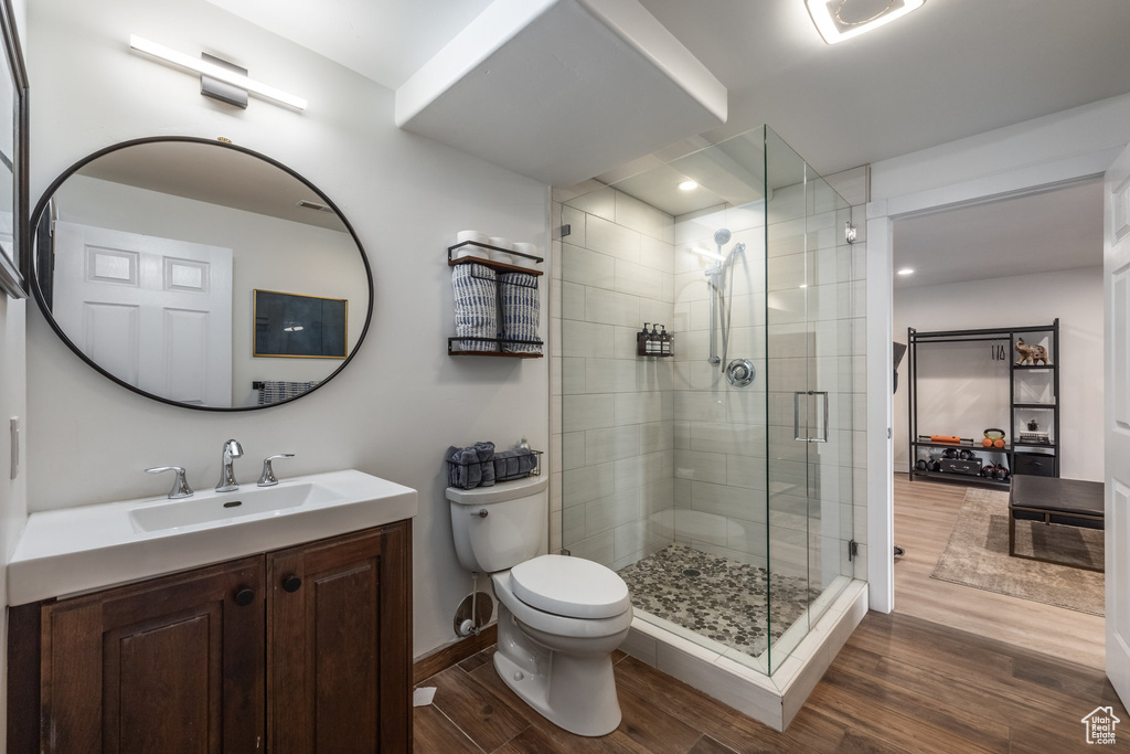 Full bath featuring wood finished floors, a shower stall, toilet, vanity, and baseboards
