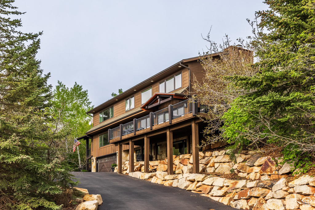 View of front of house with an attached garage, driveway, and a wooden deck
