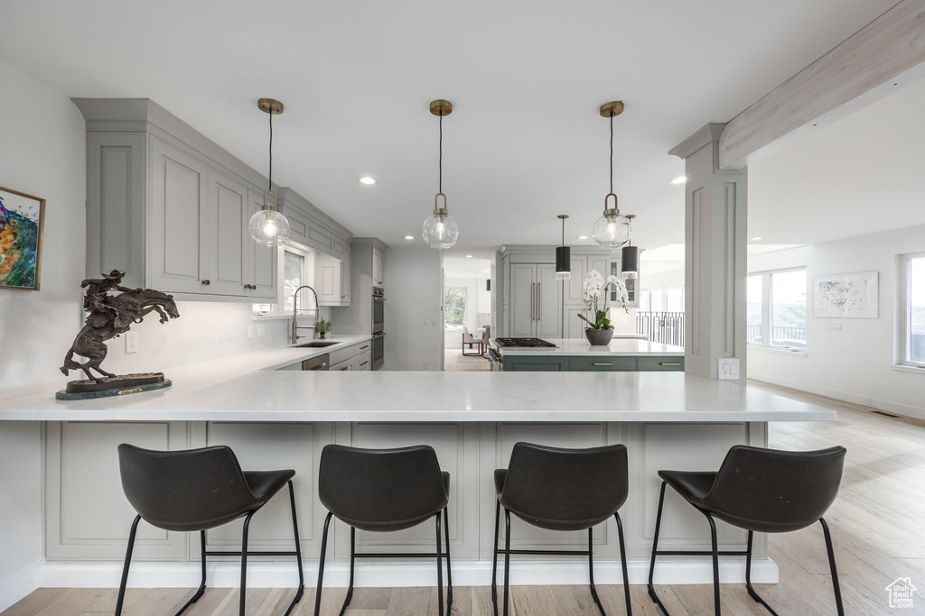 Kitchen featuring a peninsula, a sink, light countertops, gray cabinets, and recessed lighting