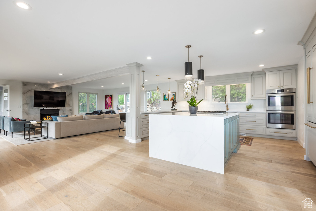 Kitchen featuring stainless steel double oven, recessed lighting, light countertops, light wood finished floors, and a kitchen island