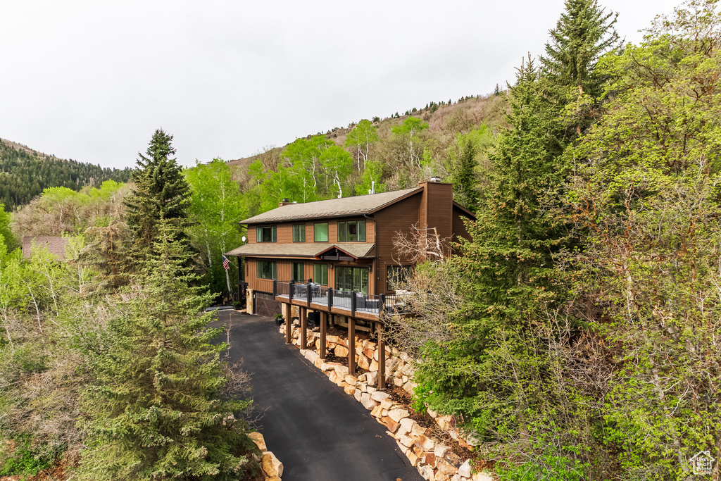 View of front facade with a chimney and a view of trees