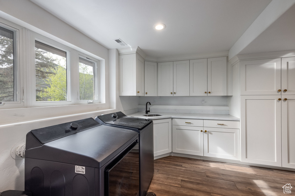 Washroom featuring separate washer and dryer, cabinet space, dark wood-type flooring, and recessed lighting