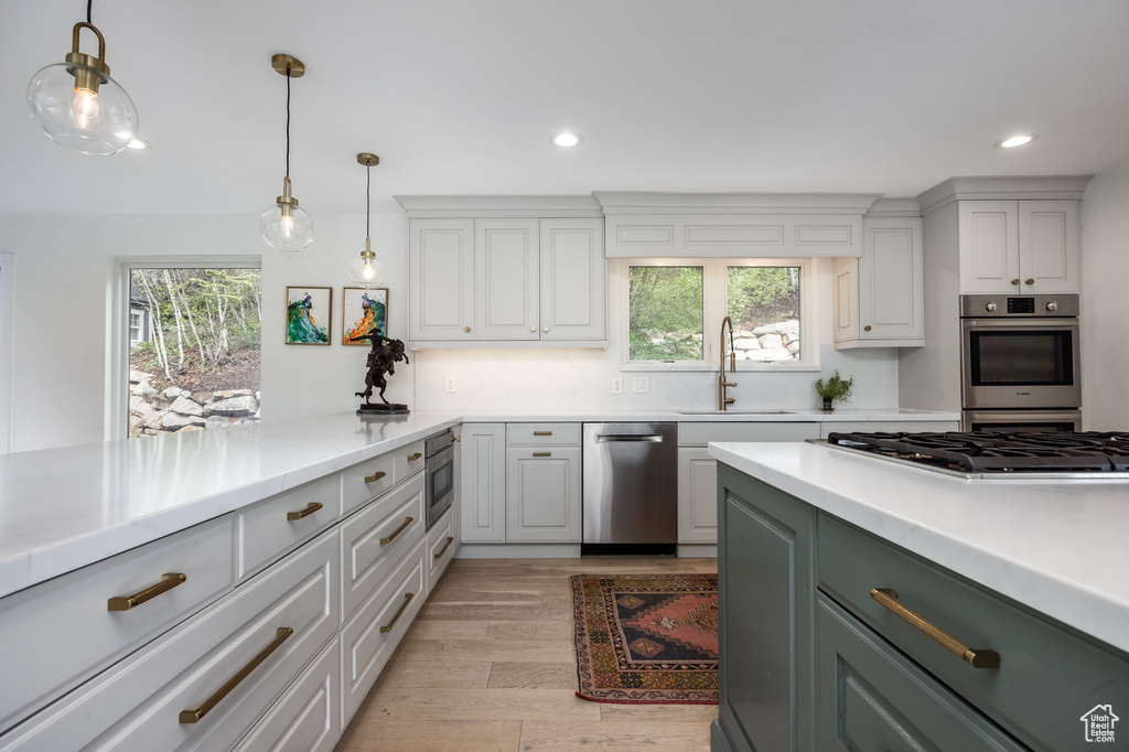 Kitchen with a sink, stainless steel appliances, light wood-style flooring, recessed lighting, and light countertops
