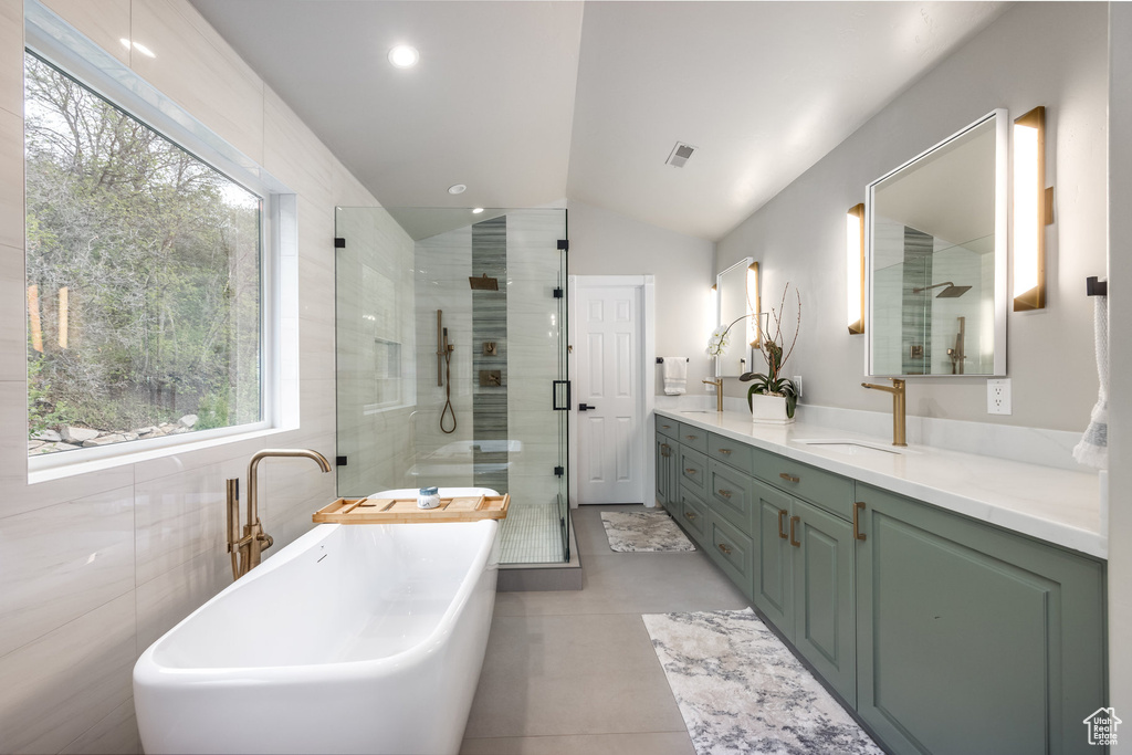 Bathroom with vaulted ceiling, a stall shower, a freestanding bath, double vanity, and tile patterned flooring