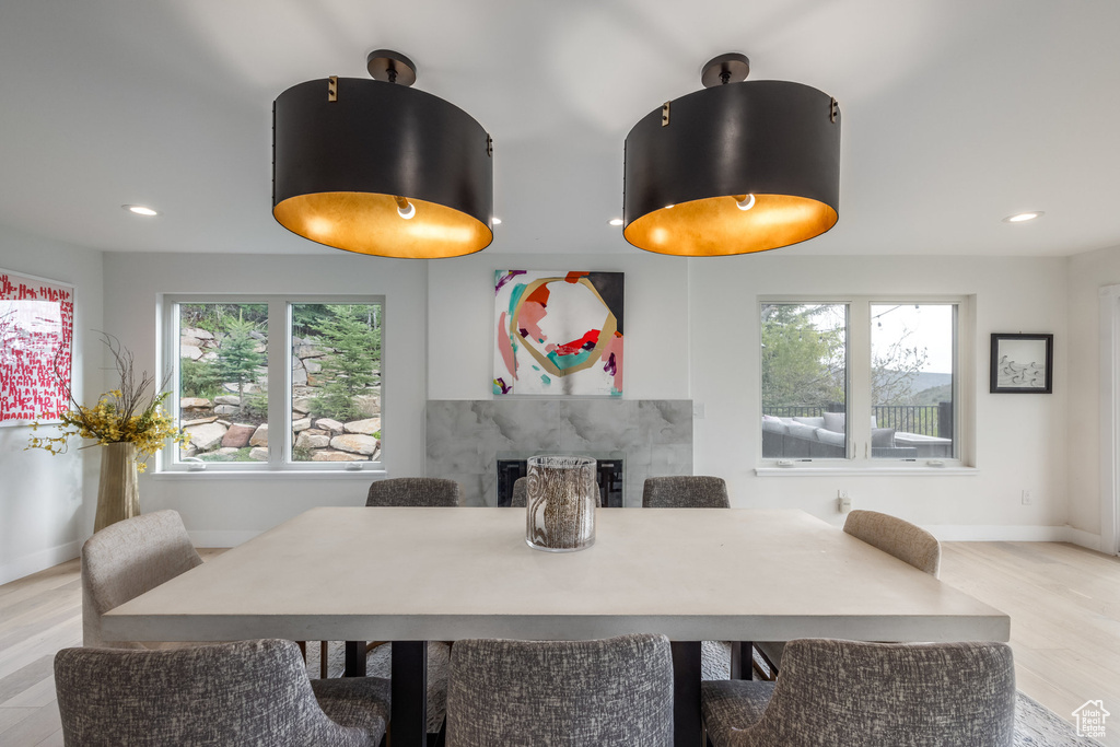 Dining area featuring a high end fireplace, baseboards, light wood finished floors, and recessed lighting