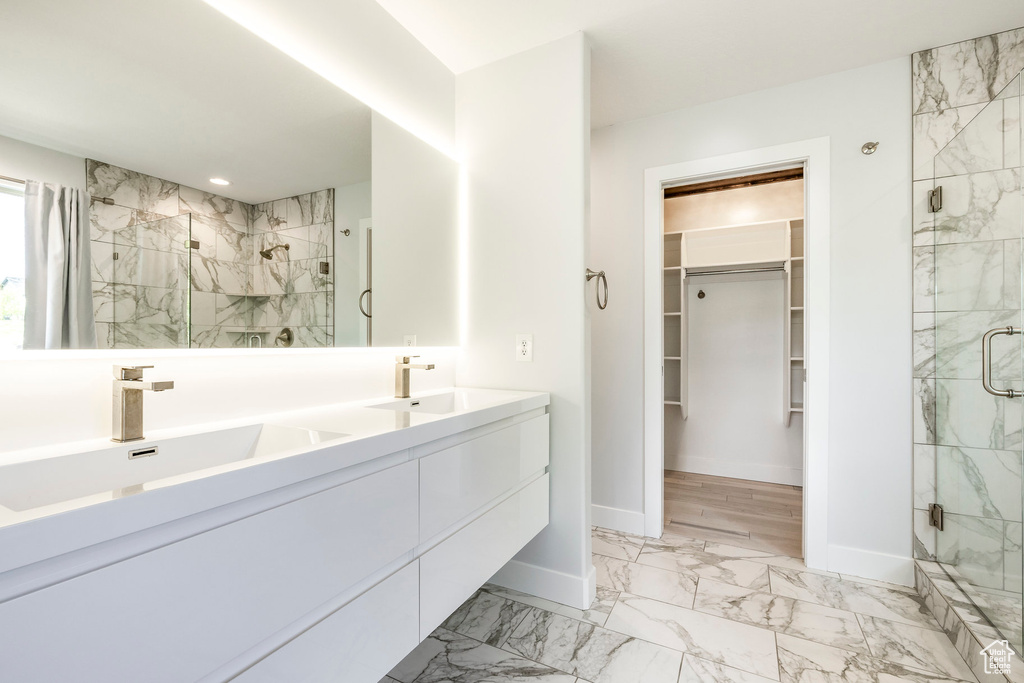 Bathroom with a marble finish shower, a walk in closet, marble finish flooring, double vanity, and recessed lighting