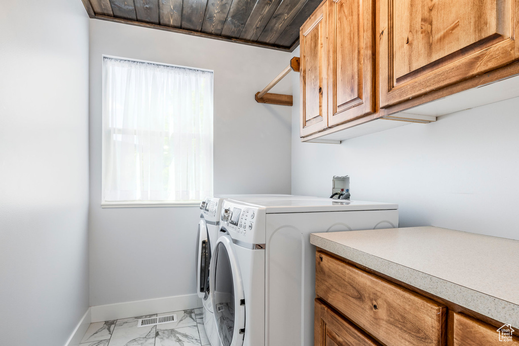 Washroom featuring washer and clothes dryer, baseboards, cabinet space, and light marble finish flooring