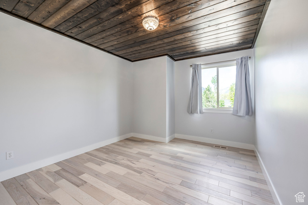 Spare room with wooden ceiling, light wood-type flooring, and baseboards