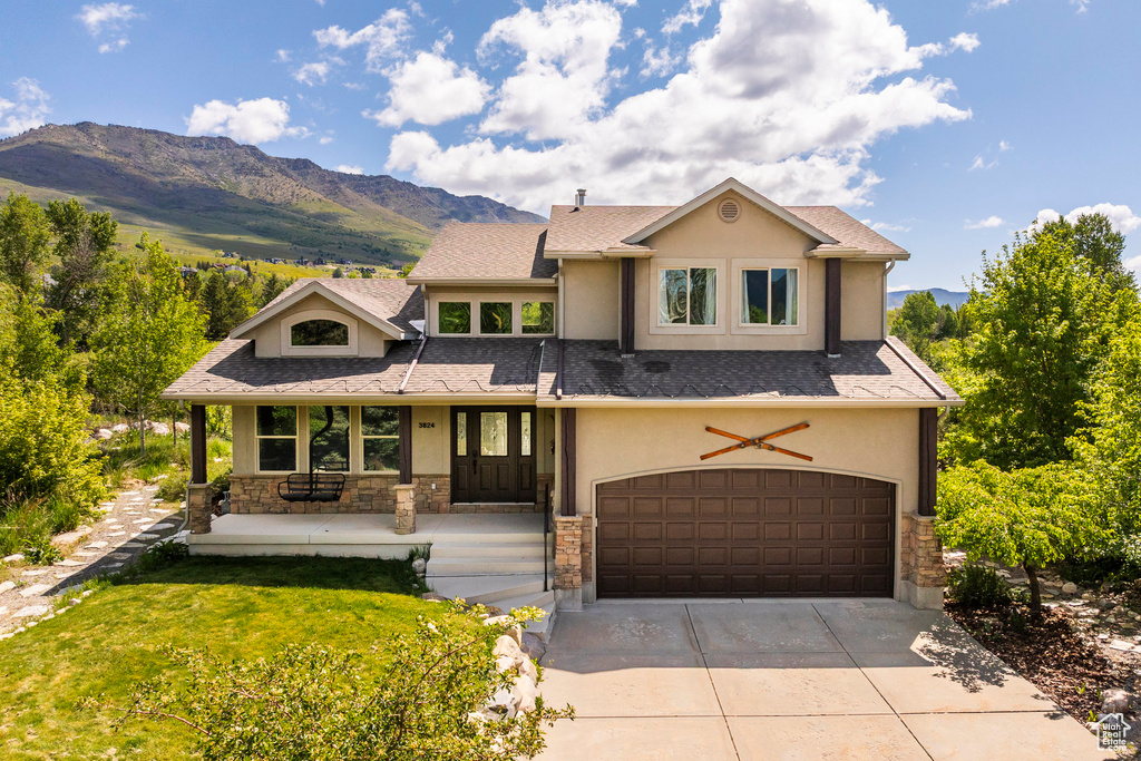View of front of house featuring stucco siding, an attached garage, stone siding, covered porch, and concrete driveway