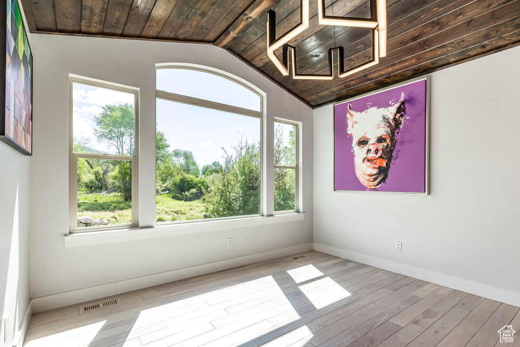 Spare room featuring lofted ceiling, light wood-style flooring, wooden ceiling, and baseboards
