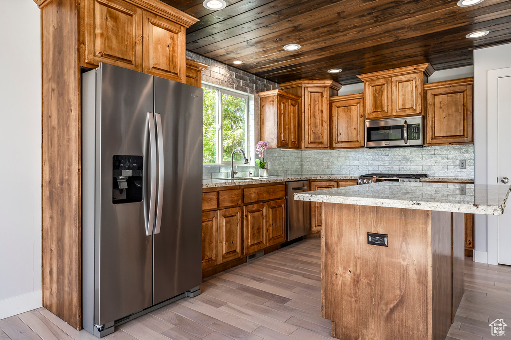 Kitchen featuring stainless steel appliances, brown cabinetry, wood ceiling, light wood-style floors, and a sink